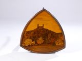 un objet en bois de forme triangulaire sur lequel est représenté un château