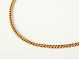 a close up of a gold chain necklace on a white surface