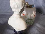 a white bust of a man next to a blue vase