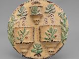 an image of a decorative plate with a cross and leaves on it