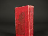 an old red book sitting on top of a black surface