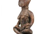 an old wooden statue of a woman sitting on a black base