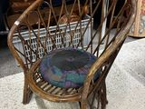 une chaise en osier avec un coussin posé dessus, dans une pièce