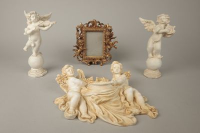 trois statues d'anges et un cadre photo posés sur une table