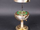 a silver and gold table lamp with a green globe on it