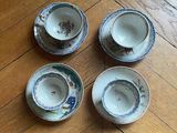 four small cups and saucers sitting on a wooden floor