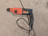an orange and black electric drill sitting on the ground next to a black cord