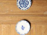 trois assiettes bleues et blanches posées sur un plancher en bois