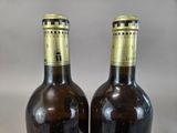 two bottles of wine sitting on top of a table next to each other
