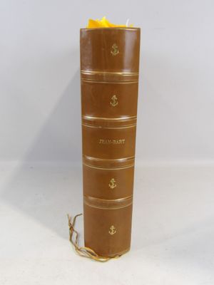 un vieux livre marron sur lequel est posée une bougie jaune
