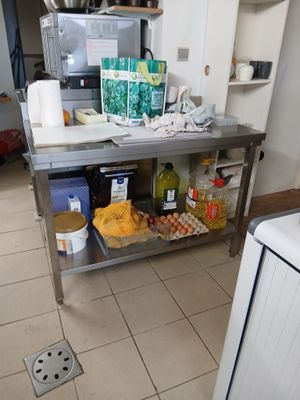 une cuisine équipée d'une table en inox et d'un micro-ondes