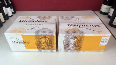 deux cartons de vin posés sur un comptoir, à côté de bouteilles de vin