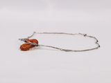a silver bracelet with an orange leaf charm on it