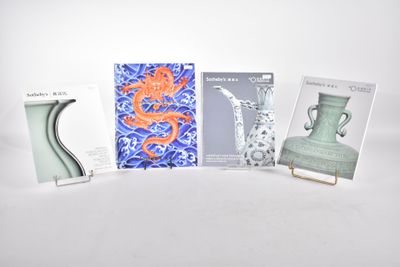 quatre livres exposés sur une table où se trouvent également des vases