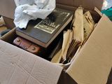 une boîte en carton remplie de livres et de papiers, posée par terre