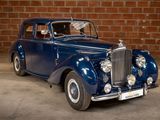 a blue car that is parked in front of a brick wall