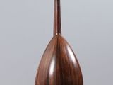 a wooden mandolin hanging from a string on a gray background