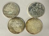 four different british coins sitting on top of a white surface