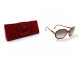 une paire de lunettes de soleil et un étui rouge posés sur une surface blanche, sur fond blanc