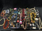 many different necklaces and bracelets laid out on a table