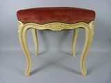 un banc rouge et blanc avec des finitions dorées et un coussin d'assise rouge