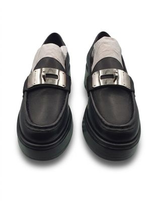 pair of black and white shoes with silver buckles on a white surface