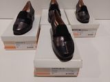 trois paires de chaussures noires exposées sur une table