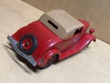 une petite voiture rouge avec un toit beige posée sur une table