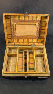 une petite boîte en bois compartimentée posée sur une surface noire