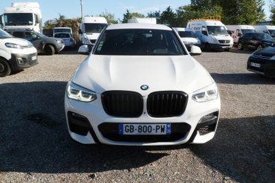 a white bmw suv parked in a lot with other cars