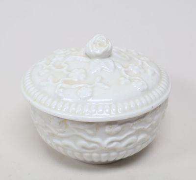 un bol blanc avec un couvercle posé sur une table blanche