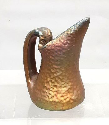 a brown pitcher with a handle sitting on a white surface