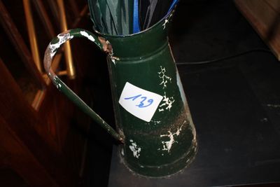 un vase vert contenant des parapluies, posé sur une table