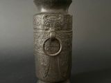 a silver vase with a ring on it on a black surface