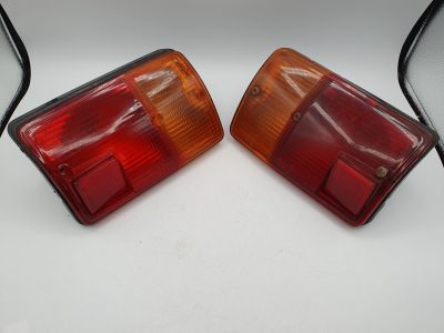 une paire de feux arrière rouges et jaunes sur une surface blanche