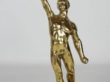 brass figurine of a man holding a tennis ball and a tennis racket