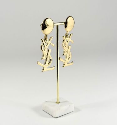 une paire de boucles d'oreilles en or posée sur un socle en marbre