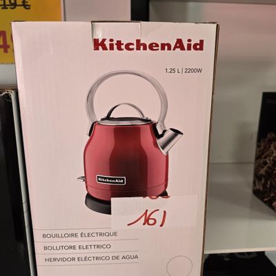 une bouilloire rouge qui se trouve dans la boîte posée sur l'étagère