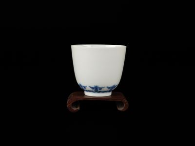 a white cup sitting on a wooden stand on a black background