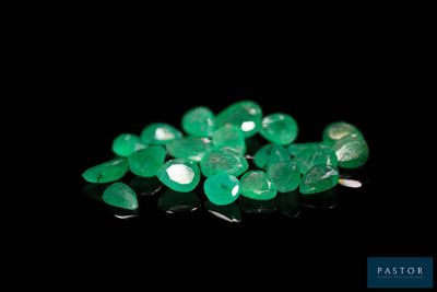 a close up of a bunch of green gems on a black surface