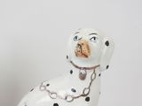 dalmatian dog figurine sitting on a blue base with a chain around it ' s neck