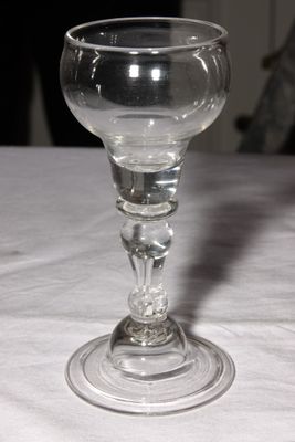 a wine glass sitting on a table with a cat in the background