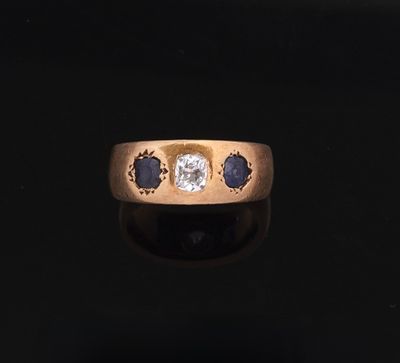 a close up of a gold ring with a diamond and sapphire stones