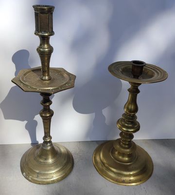 pair of antique brass candlesticks on display in front of a white wall