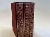 two red books sitting on top of each other on a white surface