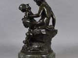 an image of a bronze statue of a woman sitting on a rock