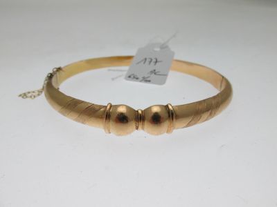 gros plan d'un bracelet en or sur une surface blanche