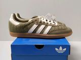 a pair of adidas trainers in gold and white on a blue box