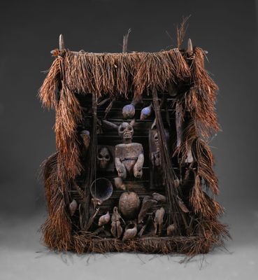 une sculpture représentant un homme dans une hutte, entouré de nombreux objets