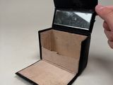 a person holding a small black box with a mirror in it
